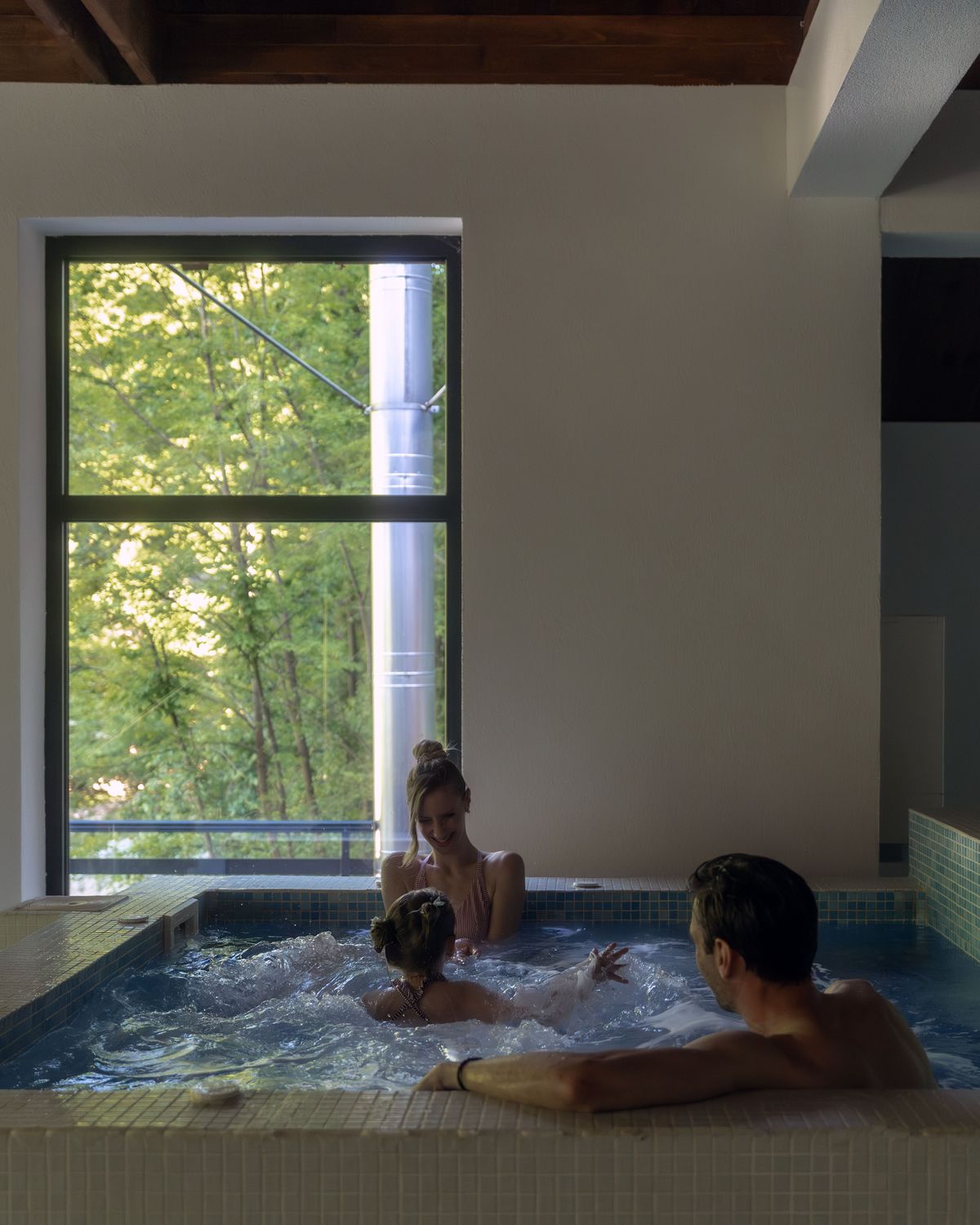 Gosti u jacuzziju Lepog Mesta uz prozor sa pogledom na šumu Lisina